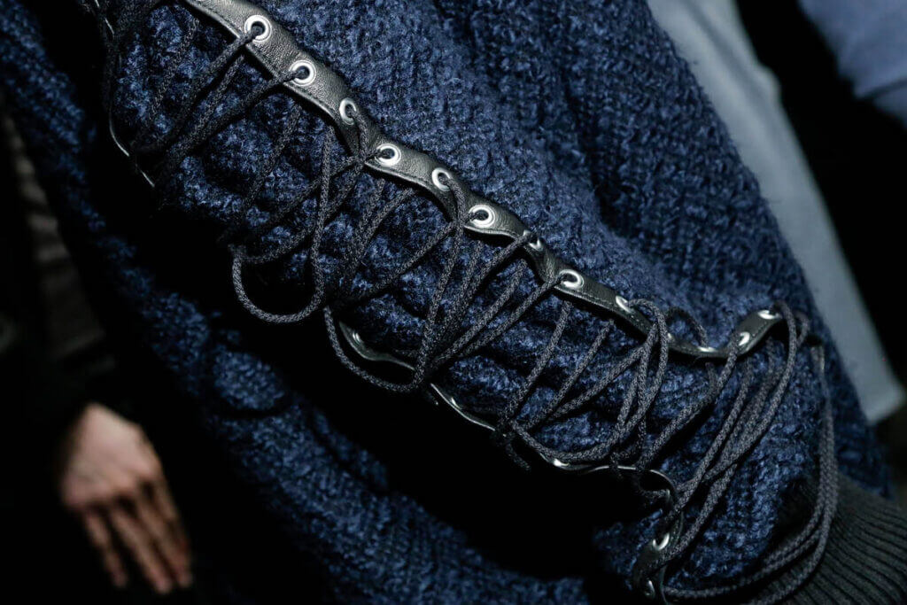 Navy sweater with laced sleeve detail.