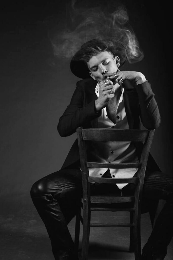 JANBOELO model smoking, seated on chair.