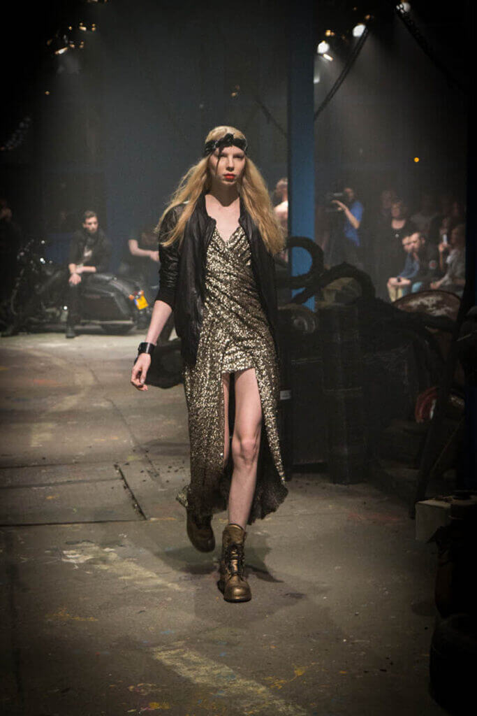 JANBOELO Fall Winter 2015 collection presentation at Paradigm Groningen, Model in gold paillet dress with leather coat on runway