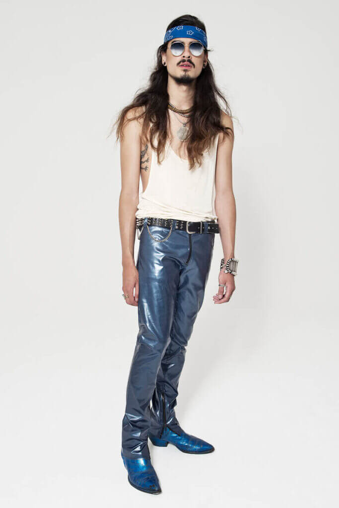 JANBOELO lookbook shot by Robin de Puy for spring summer collection look 1, Man in shiny blue trousers and accessories.