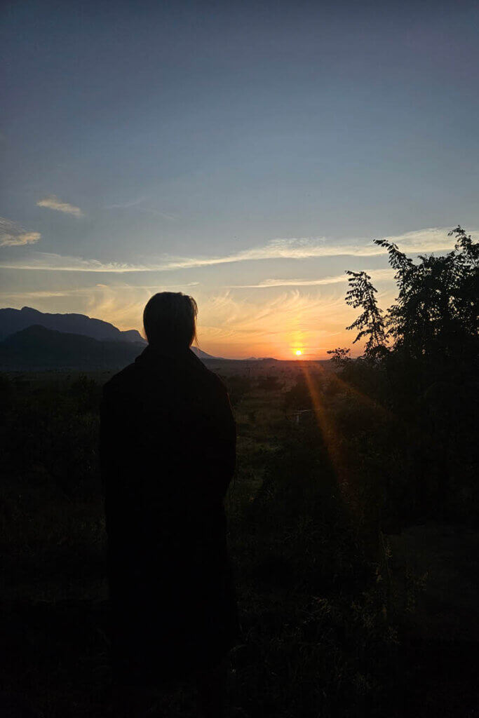 Sunrise over the mountains in Pian Upe Uganda with a person overlooking the landscape, reflecting the slower rhythm of daily life in karamoja