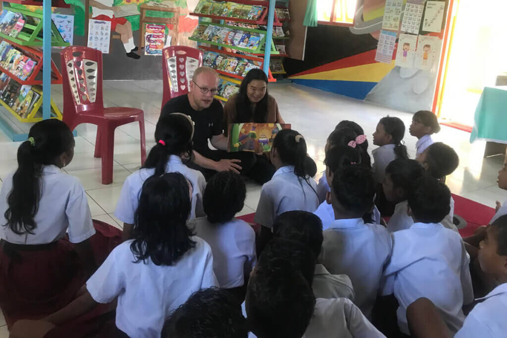 Jan Boelo reading with children in a classroom on Saparua Island while learning about education in the moluccas from Heka Leka