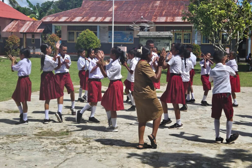 Enthousiast teacher dancing with children whilst showcasing education in the Moluccas Indonesia