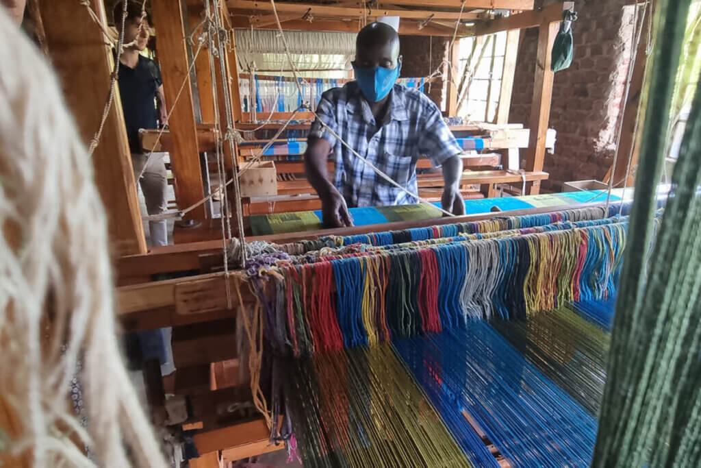Person in a weaving workshop showing the crafstmanship and making of hand woven items in Uganda