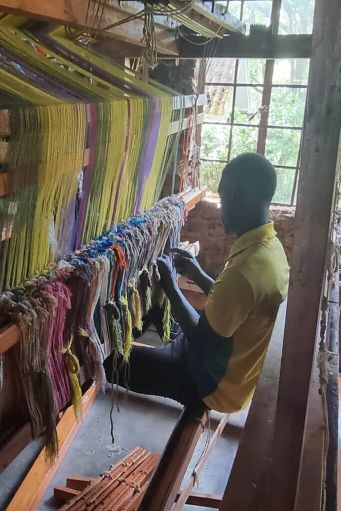 Artisan demonstrating why craftsmanship matters while preparing a loom in a workshop in Uganda